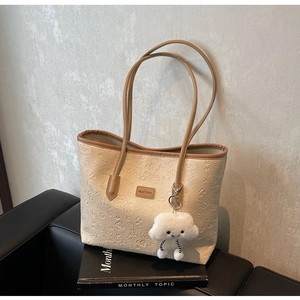 Dettaglio della borsa tote beige con motivi a cartoni animati e ciondolo a nuvola
