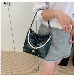 Détail du sac seau matelassé noir avec perles élégantes et pendentif étoile brillant