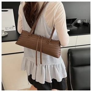 Detailed close-up of brown woven leather texture and elegant zipper tassels on underarm bag