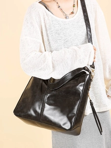 Classica borsa a secchiello nera lucida con nappe e dettagli metallici dorati