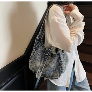 Detail of vintage denim tote bag featuring metal rivets and adjustable belt buckle closure