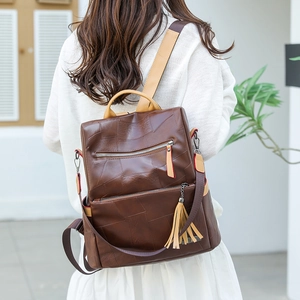 Detail of a brown fashion backpack with patchwork texture and decorative tassel on a model