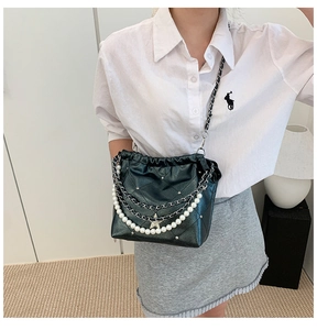 Détail du sac seau en cuir matelassé vert foncé avec chaînes et perles nacrées