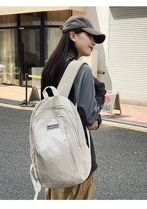 Detail of minimalist cream canvas backpack with wide shoulder straps and side pocket