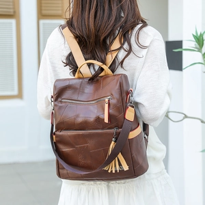 Outdoor shot of a stylish brown geometric patchwork backpack with fringe detail
