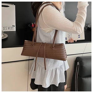 Close-up of brown woven leather baguette bag showing texture and shoulder strap