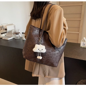 Vista laterale della borsa tote in pelle marrone con motivi a sbalzo e ciondolo a nuvola