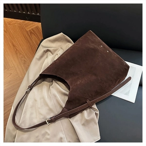 Detail view of dark coffee suede tote bag with adjustable strap on a chair