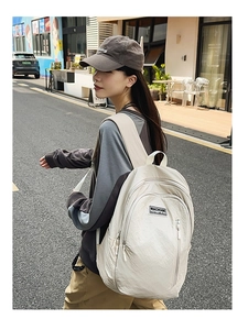 Close-up of stylish off-white nylon backpack featuring a brand logo and pleated texture