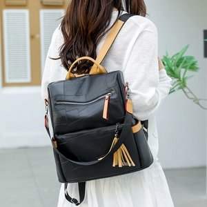 Outdoor shot of a black PU leather backpack with tassel detail and brown handle