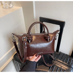 Detailed view of brown glossy PU leather Boston bag with knotted handles and logo