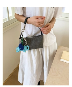 Detail of woven fabric texture on a gray shoulder bag with blue leather elephant charm