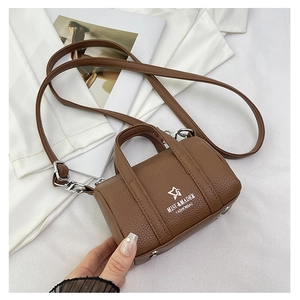 Macro detail of brown litchi pattern leather mini bag with silver metal buckle