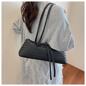 Detail of black woven leather shoulder bag showing intricate texture and side tassel trim