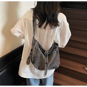 Detail of vintage washed denim hobo bag with adjustable wide strap and metal eyelets