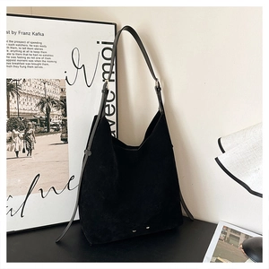 Detail of minimalist black matte suede tote bag with slim shoulder strap and golden hardware