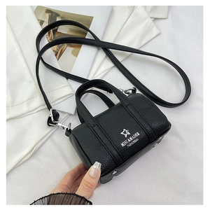 Detailed macro view of black litchi grain leather mini pillow bag with silver metal hooks