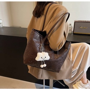 Dettaglio della borsa tote in pelle goffrata marrone scuro con ciondolo a nuvola
