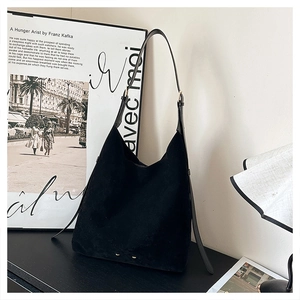 Close-up of black matte suede hobo bag with adjustable leather strap in a minimalist setting