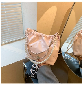 Détail du sac seau rose matelassé avec chaînes en perles et breloques étoiles en strass