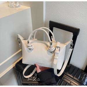 Chic beige crossbody pillow bag displayed on luggage with stylish handle hardware