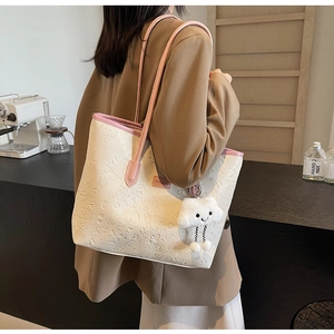Dettaglio borsa tote color crema con cuori a rilievo e un ciondolo a nuvola morbida