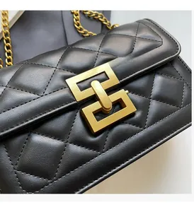 Détail de cuir matelassé noir avec fermoir géométrique doré et bandoulière chaîne
