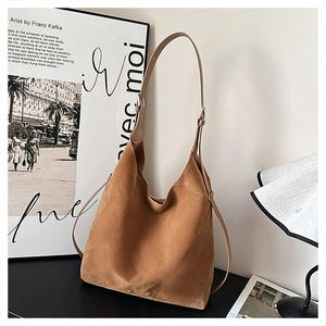 Detail of a brown matte suede hobo bag featuring wide shoulder straps and side tie accents