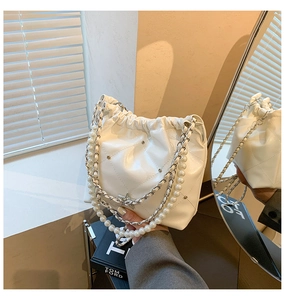 Détail d'un sac seau blanc matelassé avec anse en perles, breloque étoile et chaîne argentée