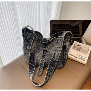 Detail of vintage washed denim tote bag with silver eyelets and wide shoulder strap