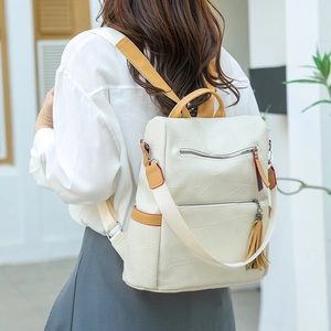 Close-up of beige PU leather backpack with yellow contrast trim and tassel on a model