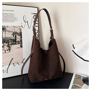 Detail of dark brown suede hobo bag with adjustable strap and gold metal buckles