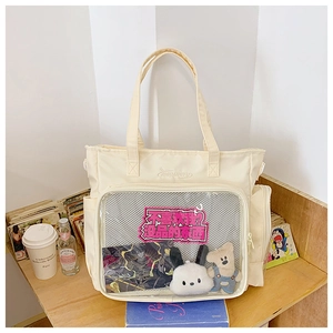 Detail of cream canvas Ita Bag with transparent PVC window displaying plush accessories