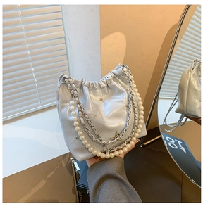 Détail du sac seau matelassé bleu clair avec chaîne en perles et breloques argentées