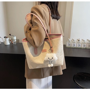 Dettaglio della borsa tote crema con manici rosa e motivi a rilievo strutturati