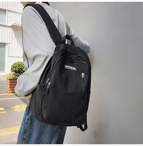 Detail of black nylon backpack featuring multi-pocket design and silver metal zippers