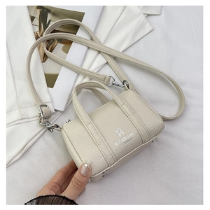 Detail of cream mini pillow bag showing pebble leather texture and silver MISU brand logo