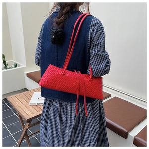 Detail of red woven leather shoulder bag with sleek dual straps and rectangular silhouette