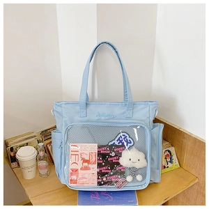 Detail of light blue nylon tote bag featuring a clear PVC window and plush cloud charm