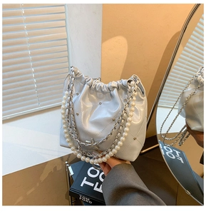 Détail d'un sac seau matelassé bleu clair avec chaîne en perles et pendentif étoile