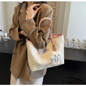 Dettaglio della borsa tote crema con bordi rosa e icone di cartoni animati a rilievo