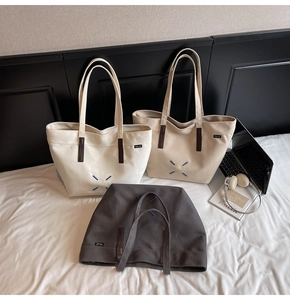 Detailed view of canvas tote bags in white and grey with chic blue X-stitch and logo tag