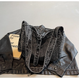 Detail of grey washed denim tote bag with metal eyelets on shoulder strap and zipper closure