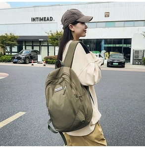 Olive green water-resistant nylon backpack for women shown in a casual street setting