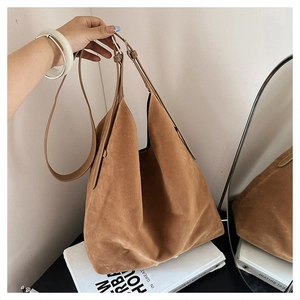 Detail of vintage brown suede hobo bag featuring adjustable leather strap and metal buckle