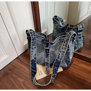 Detail view of washed blue denim tote bag with silver eyelet strap and vintage texture