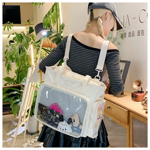 Close-up of white canvas ita bag with large transparent PVC pocket and adjustable strap