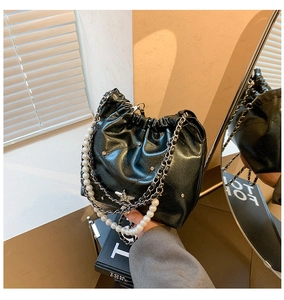 Détail du sac seau noir brillant avec chaîne en perles et ornement en étoile
