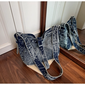 Close-up of vintage blue denim tote bag with silver eyelet straps and wash texture