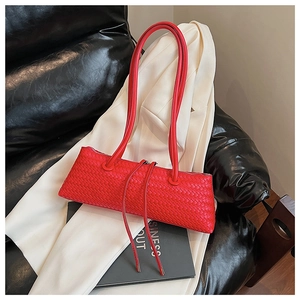 Detailed close-up of red woven leather texture and fine stitching on the minimalist handbag